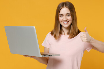 Young freelancer copywriter woman 20s wearing casual basic pastel pink t-shirt holding laptop pc...