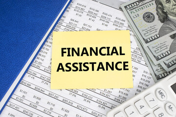 The financial aid is written on a yellow piece of paper which is located in the financial document next to a white calculator with dollars and a notepad .
