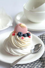 Close-up Cake Pavlova with whipped cream and fresh berries on a light background. Homemade meringues cookies