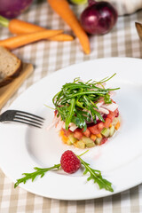 Tartare of fresh diced vegetables and salads in a white plate decorated with a raspberry , France