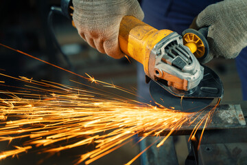 Locksmith in special clothes and goggles works in production. Metal processing with angle grinder....