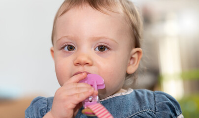 Cute baby girl biting a plastic clip