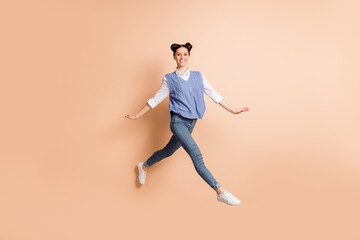 Fototapeta na wymiar Full size profile photo of brunette optimistic lady jump go wear white shirt blue vest jeans sneakers isolated on beige color background