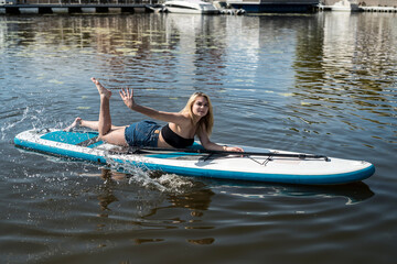 Young female surfer lying on sup board and rest at nature
