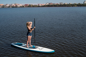 Fototapeta na wymiar pretty girl on a paddle board on the city lake