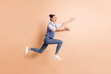 Fototapeta na wymiar Full size profile photo of brunette optimistic lady jump wear white shirt blue vest jeans sneakers isolated on beige color background