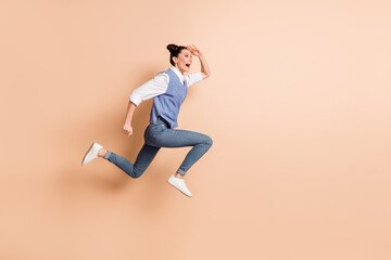 Fototapeta na wymiar Full length photo of pretty sweet girl dressed knitted waistcoat jumping hurrying looking far away isolated beige color background