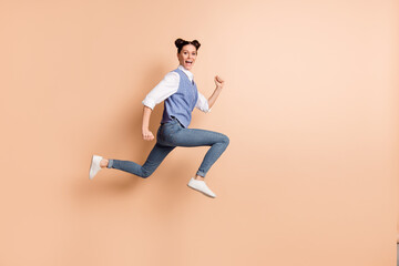 Fototapeta na wymiar Full length photo of cute adorable young lady wear blue vest jumping high running fast isolated beige color background