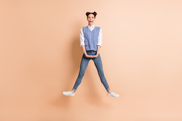 Fototapeta na wymiar Full length photo of sweet cute young lady wear blue vest jumping high legs sides isolated beige color background