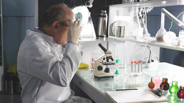 Male scientist working in modern lab, making microbiology research and studying. Using laboratory tools: microscope, test tubes, equipment. covid-19, bacteriology, virology, medicine.