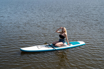 young sportive woman lying and relax on sup board blue pond water