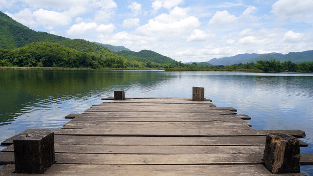 Empty wooden bridge or table top with the lake mountain and sky landscape. Wood floor with lake mountain and sky of nature park background and summer season, product display montage.