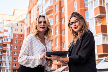buyer and realtor signs an agreement to buy an apartment  of multi-storey building on  background