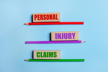 On a blue background, three colored pencils, three wooden blocks with text PERSONAL ENJURY CLAIMS