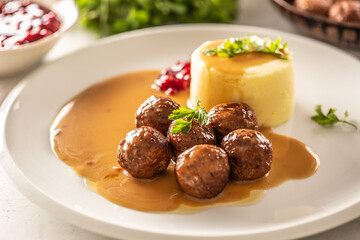 Plate serving Swedish meatballs kottbullar in sauce with mashed potatoes and cranberry sauce