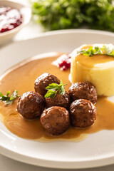 Plate serving Swedish meatballs kottbullar in sauce with mashed potatoes and cranberry sauce