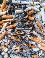 Cigarette butts stacked in a transparent glass close-up. Selective focus, photo taken through glass