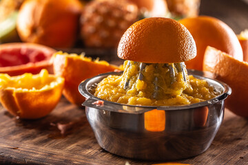 Freshly squeezed orange in a manual juicer with pulp, juice and orange skins leftovers
