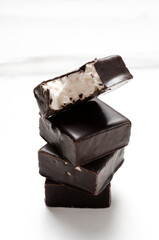 Vertical image of stack of soft candies with chocolate glaze on the white surface