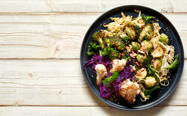 Tasty vegetarian dish with cabbages and noodles on table