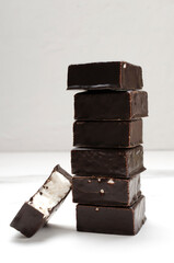 Closeup of stack of candies with chocolate glaze and soft filling on the white table