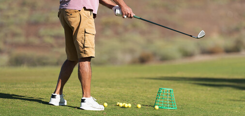 Golf player making a swing with a golf fairway wood course on the golf practice