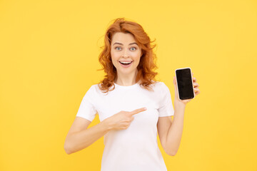 Naklejka premium excited young woman isolated overyellow background using mobile phone showing ok gesture.