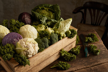 Crate with cabbages on rustic table near knife