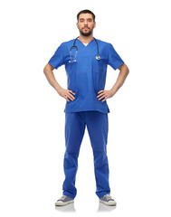 Fototapeta premium healthcare, profession and medicine concept - doctor or male nurse in blue uniform with stethoscope over white background