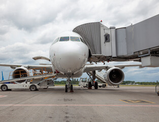 Boarding passengers on the plane through the boarding bridge. The plane lands at the international airport. Loading luggage. White airplane. Terminal Runway