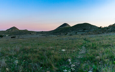 Obraz premium sunset in picturesque countryside in Andalusia with fields and a hiking trail leading to distant hills