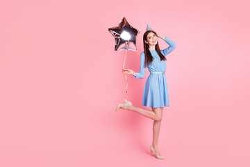 Full size photo of young smiling girl with cone on head hold balloon celebrate birthday isolated on pink color background