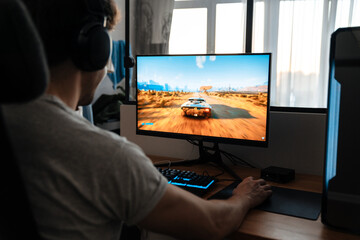 Caucasian brunette guy in headphones playing video game on his computer - obrazy, fototapety, plakaty