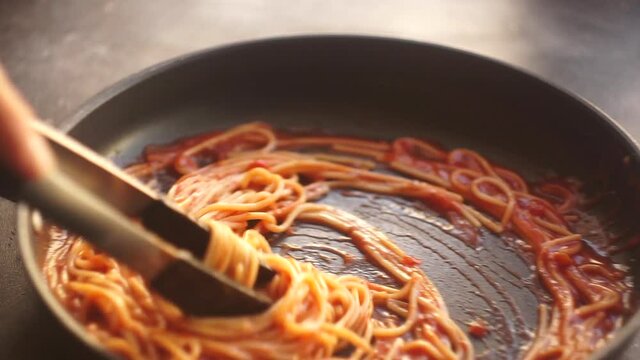 Pasta with tomato sauce. Italian spaghetti pasta with tomato sauce is cooked in a skillet in the kitchen. Italian Cuisine.