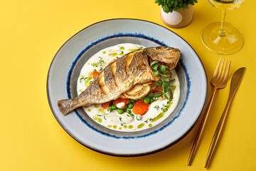 Close up of oven baked fish on on a yellow background. Healthy seafood.