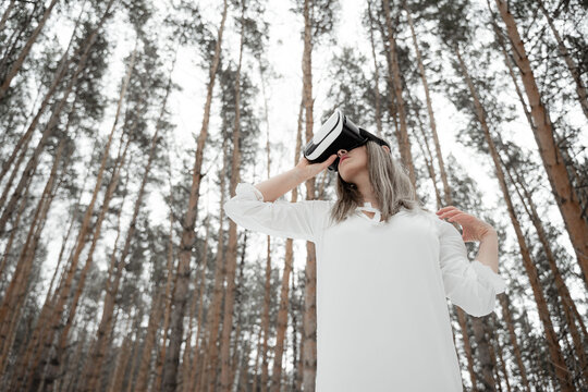 girl in virtual reality glasses stands in the winter cold forest