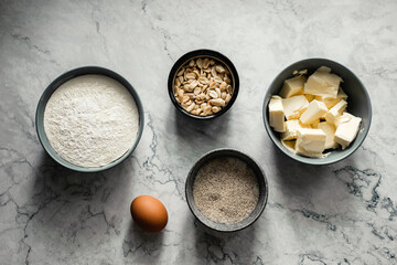 Obraz na płótnie Canvas Ingredients for baking cookies. Flour, sugar, vanilla, salt, butter, peanut, egg. Top view horizontal photo, marble backdrop