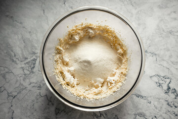 Baking cookies. Flour, baking powder and salt added to the dough in a big glass bowl. Top view...