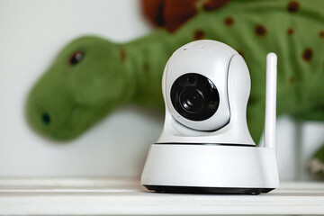 IP camera on the shelf with toys, serving as baby monitor