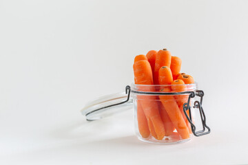 Group of carrots in a glass mason jar on white background, copy space