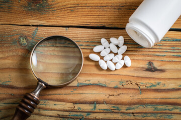Obraz na płótnie Canvas Medicine with packaging and magnifying glass on a wooden background