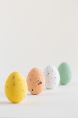 Four pastel colored chocolate Easter eggs, one pink egg sharp, on white background, copy space