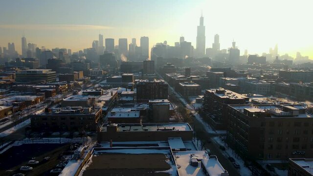 aerial drone establishing shot footage of Chicago downtown area during the winter time early in the morning after sunrise.  the white snow covers most of the city architecture landscape.   