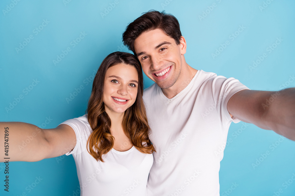 Sticker photo of optimistic couple doing selfie wear white t-shirts isolated on teal color background