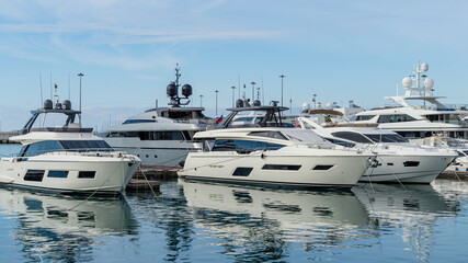 Fototapeta premium Ships, yachts and boats on blue surface of Black Sea by pier of Commercial seaport of Sochi. Resort city center. Sochi, Russia - November 23, 2020