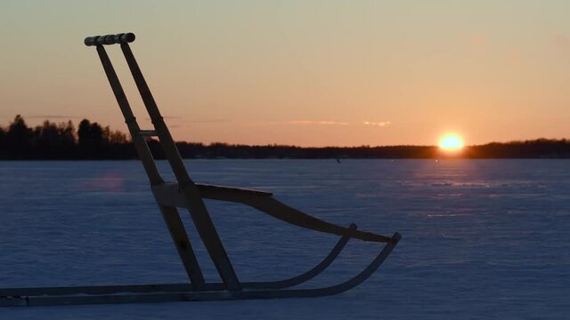 Beautiful winter landscape during sunset and a kick sled, also known as snow kick, in retro wooden material. Footage made in Sweden.