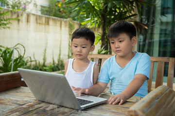 Two children use computer laptop  e-education. Distance Learning, Home Learning. Two brother stay at home concept.