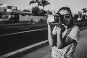 Black and white photo of a girl in sunglasses with a professional camera makes a photo in the summer.