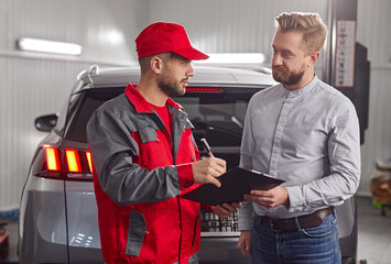 Customer and mechanic with checklist discussing work in auto service center