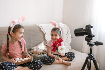 Two cute little girls posing in front of the camera with Easter eggs and flowers.